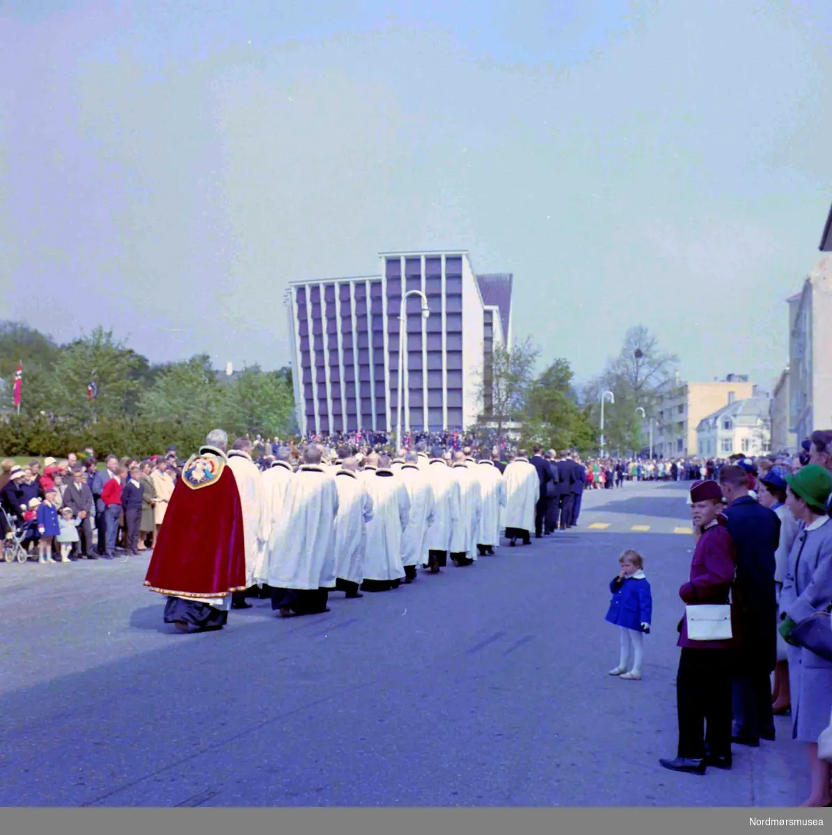 Kirkelig prosesjon. Fotografiet er trolig fra innvielsen av Kirkelandet kirke den 24.mai 1964, på Kirkelandet i Kristiansund. Fotograf er Nils Williams. Fra Nordmøre museums fotosamlinger.