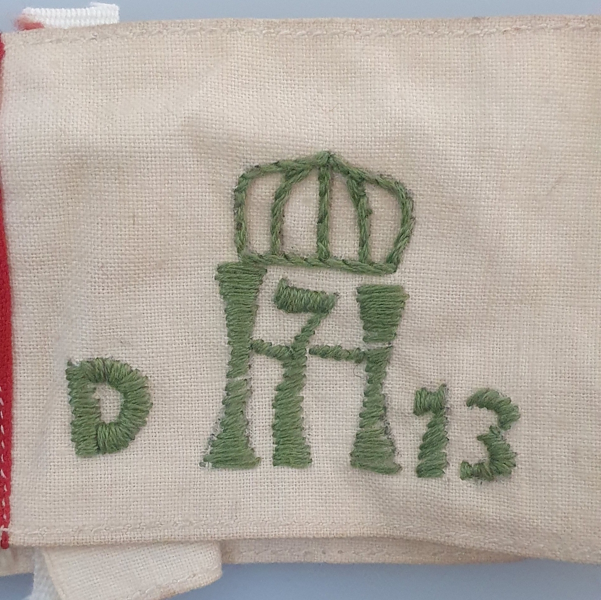 I tillegg til flaggstriper, H7-logo med krone over, og med D på venstre side og 13 på høyre side. Logoen er opprinnelige stemplet på stoffet, men deretter brodert med grønn tråd.