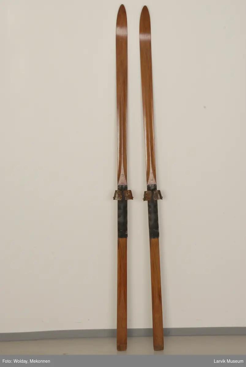 Teknikk: tilkuttet og pusset tre, gummi festet med jernstifter på baksiden av bindingen, opp- høyd midtdel på oversiden av skiene, 25 cm
Form: enkel
