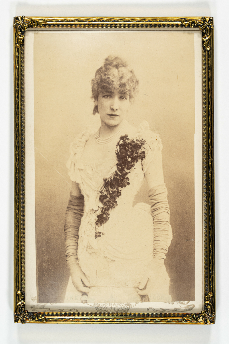 Fotografi av kvinne kledt i kjole med blomsterdekor og lange selskapshansker.