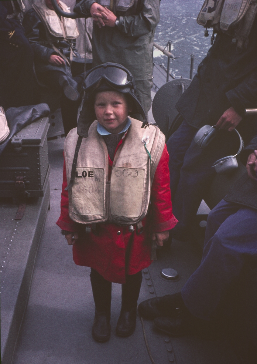 Bilden visar ett barn i skyddskläder ombord på en motortorpedbåt.