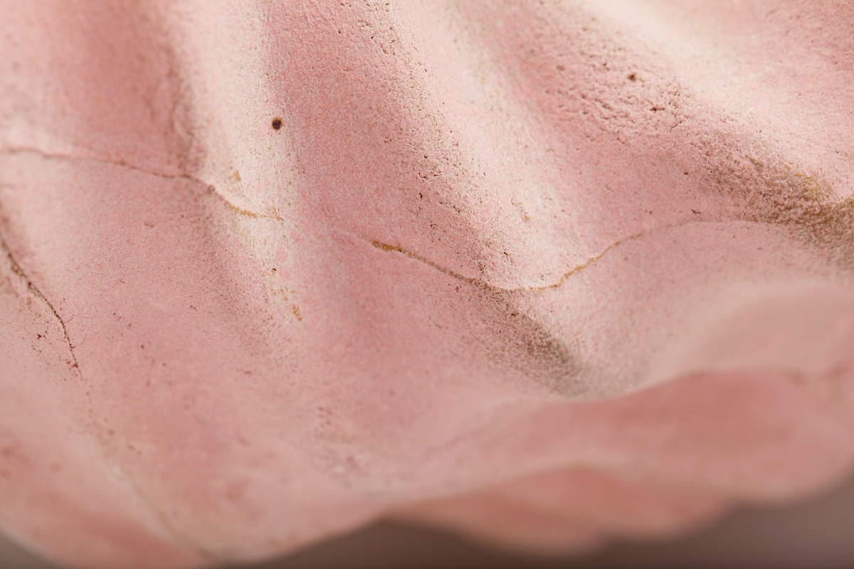 Objektet minner om en blanding av en musling og et fat. Den er hovedsaklig rosa. En mørkere jordfarge skinner gjennom. Den har også en stor hvit flekk. Undersiden er gulaktig med rosa flekker. Mønsteret kan beskrives som en spiralaktig bølge som samler seg mot midten av formen. Den kan minne om et dragsug i vannet eller spor av bølger i sanden. Mønsteret er helt integrert i formen. 


Beskrivelse av teknikk: 
Formen tilvirkes gjennom modellering. Deretter foretas en gipsavstøpning. Leiren flatkjevles og innsettes med ulike mønstre og strukturer før den presses inn i gipsformen. Under brennings- og tøkingsprosessen påføres like glassurer og oksyder. Gjenstanden brennes mellom 5-10 ganger for å oppnå de ønskede overflatevirkningene.