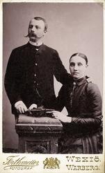 Foto (grupporträtt) av en man och en kvinna. Han är klädd i 