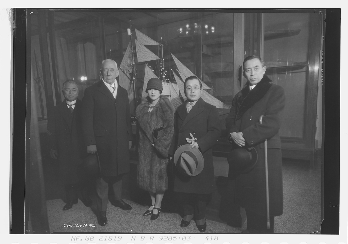 Roald Amundsen står sammen med prins Ri og prinsesse Masako. Polarskuta Fram står utstilt i bakgrunn. Datert Oslo 14/11-1927.
