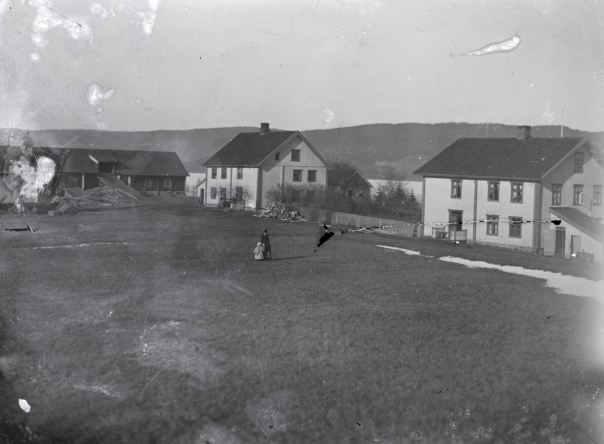 Prospektfotografi av Byrud gård ved Minnesund. To barn står på marken foran husene. Her startet Edward Yates Aston gruvedrift etter smaragder i 1899.
