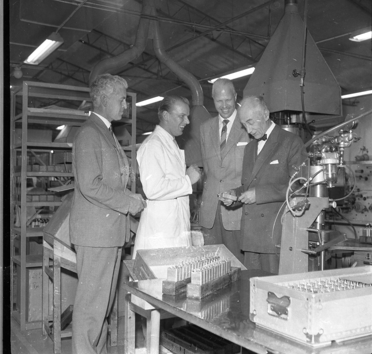 Fyra män samlade vid en arbetsstation på Rifa-fabriken i Gränna. De är från vänster: K Mörner, möjligen platschef B Arding, direktör T Skytt och troligen landshövding A Nordenstam.