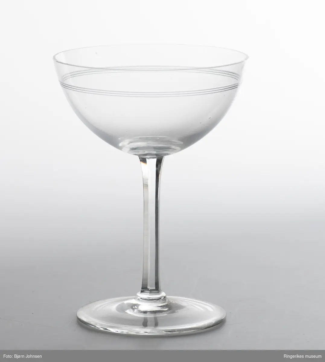 To champagneglass med sekskanta stett. To tynne og tette slipte striper øverst på glasset.