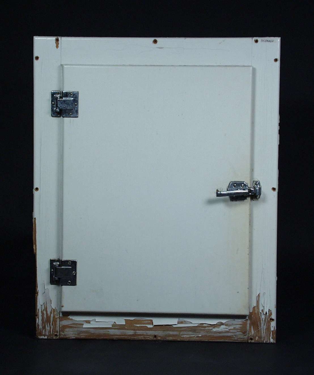 Et hvitt kjøleskap med tre hyller, håndtak og hengsler i metall.
Fronten er i treverk.
Kjøleskapet var tilpasset for å være innebygget.