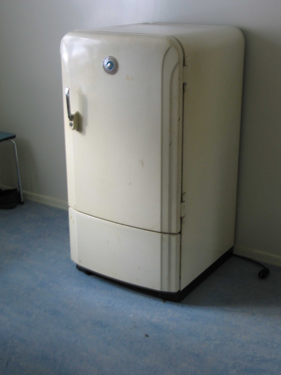 Hvitt kjøleskap med avrundede hjørner og metallhåndtak med lås.