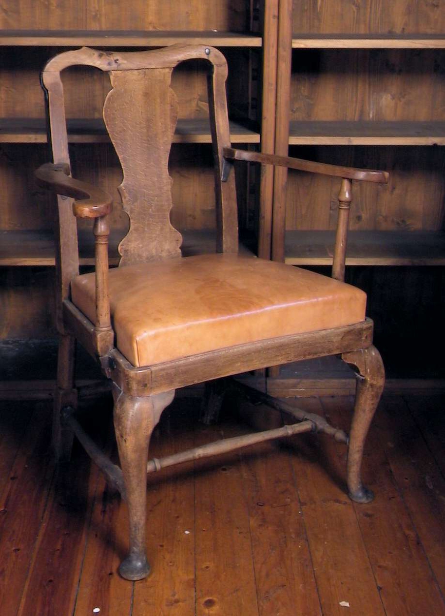 Armstol med stoppet, løst sete med skinntrekk. Stolen har forsterkninger av jern under armlenene og på toppen av ryggstø.