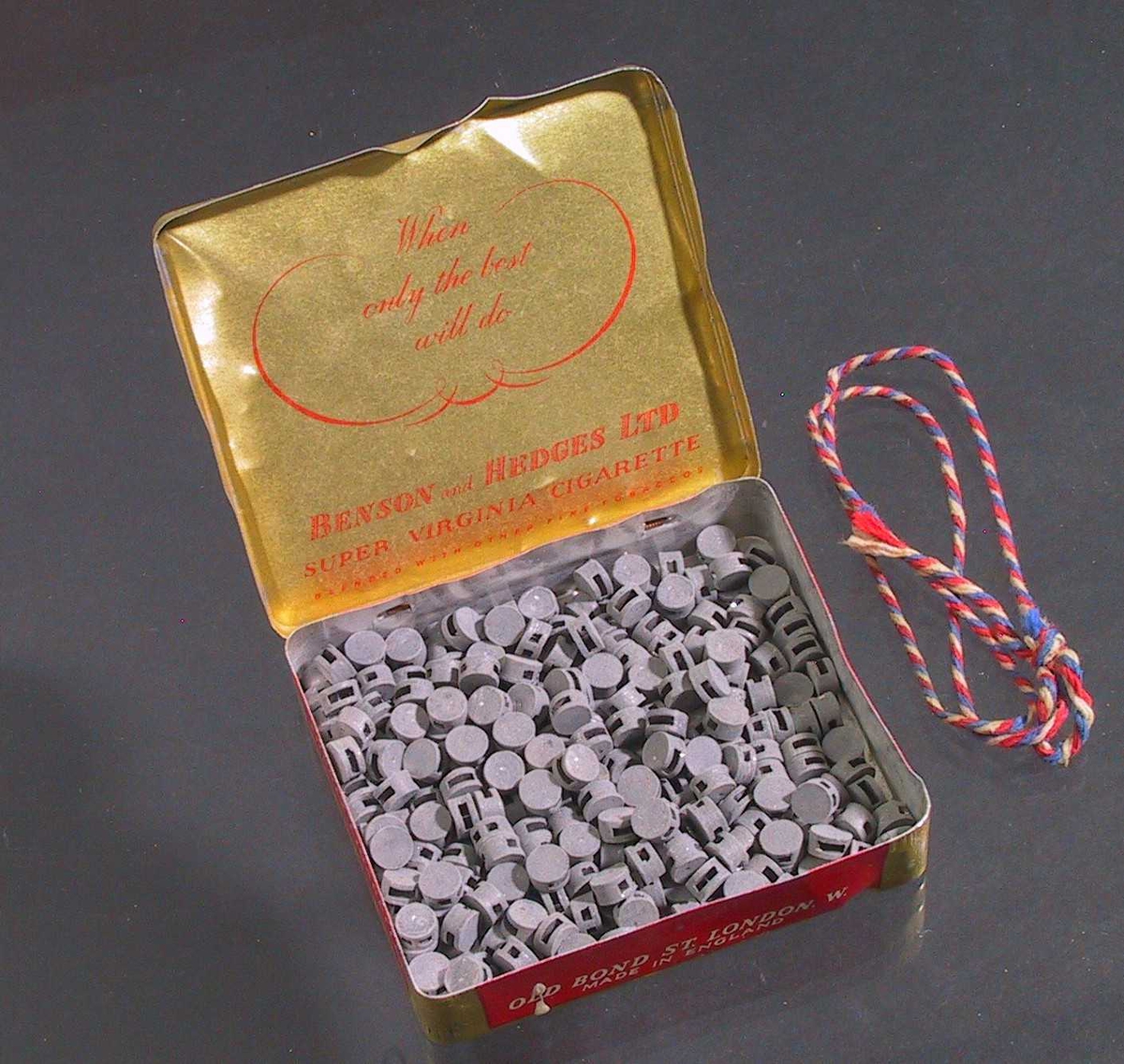 Tollplomber av bly, ligger i rød- og gullfarget sigaretteske "BENSON and HEDGE".
Brukt sammen med tang av typen AAM.30621.
