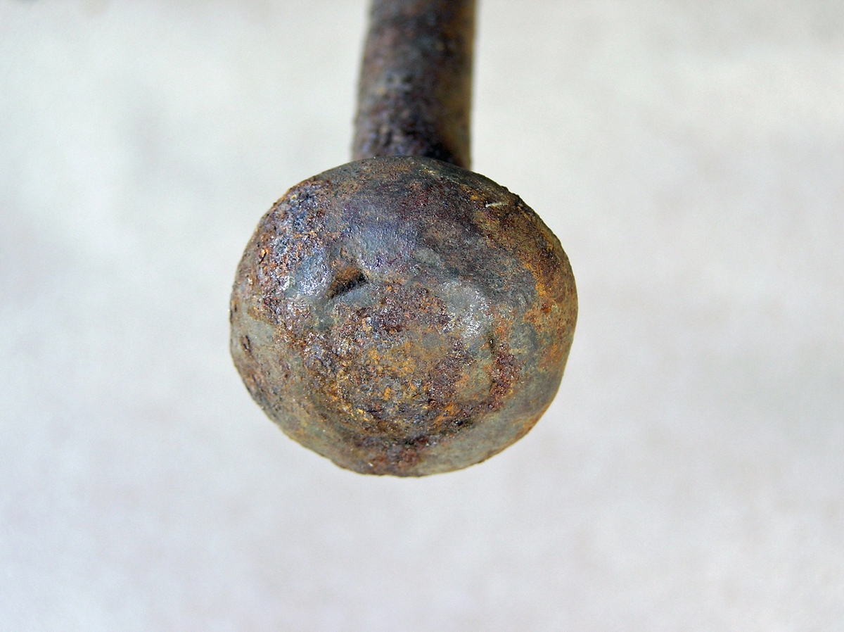Rund jernstang med påsveist kule og smal, bladformet spiss. Har muligens vært brukt til å fjerne slagg i lufterøret mellom vifta og essetrauet i smia. En del rust.
