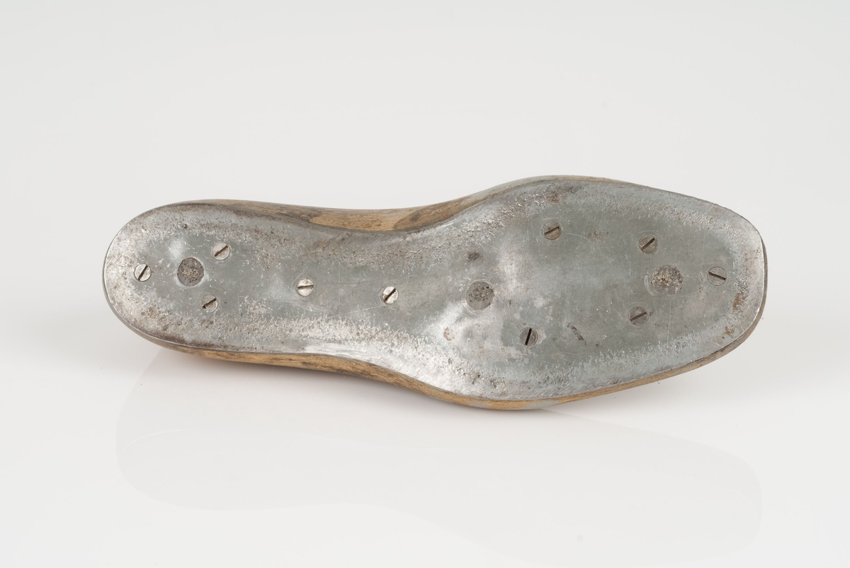 En tremodell i to deler; lest og opplest/overlest (kile).
Venstrefot i skostørrelse 42, og 8 cm i vidde.
Såle i metall.