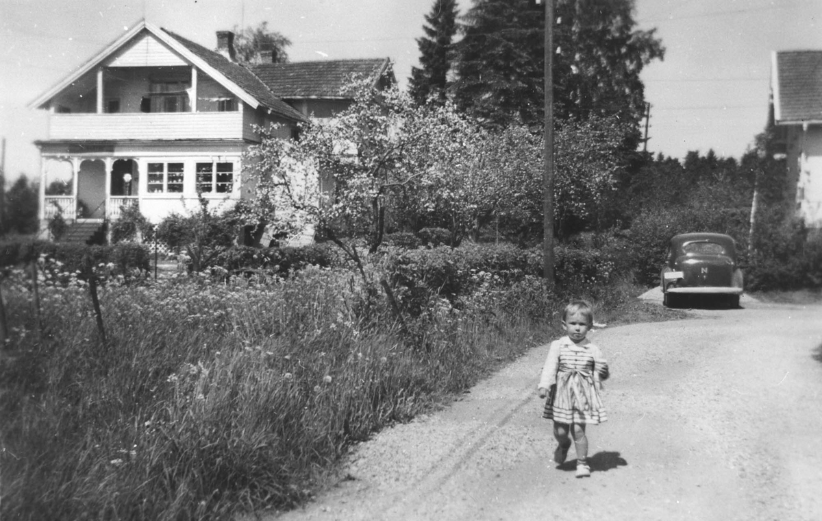 Aasvang eller Bråthe gården, bygget i begynnelsen av 1900 århundre. Bente Gundersen, tre år gammel, på vegen ved huset. Bil i bakgrunnen.