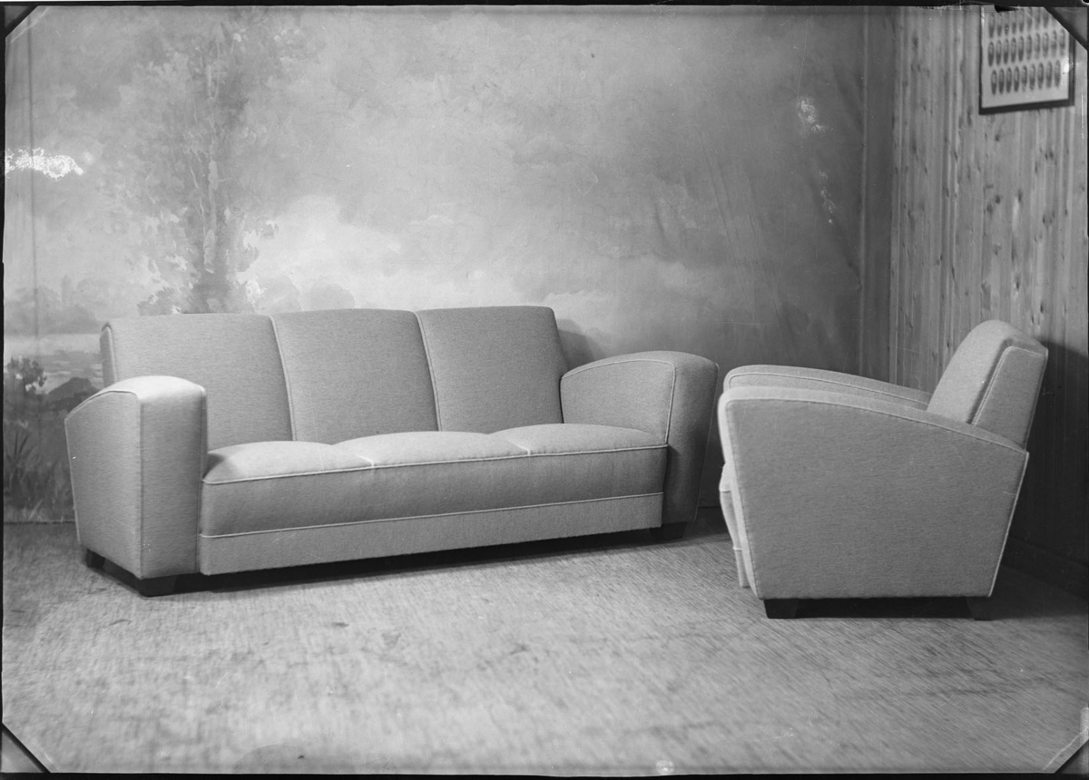 Studio opptak av en stol og en sofa.