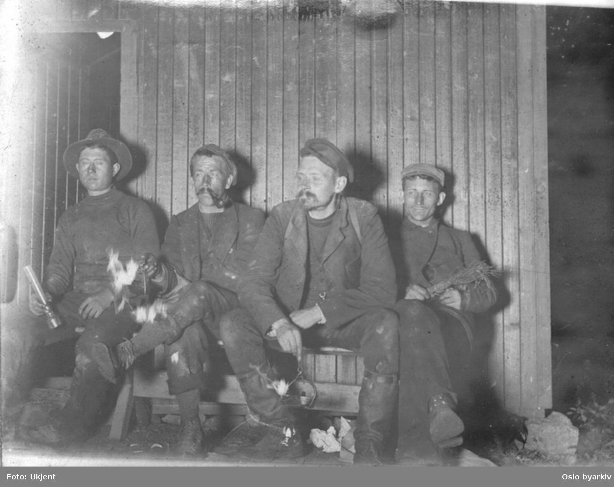 Fire arbeidere eller tømmerfløtere tar en pause i koia