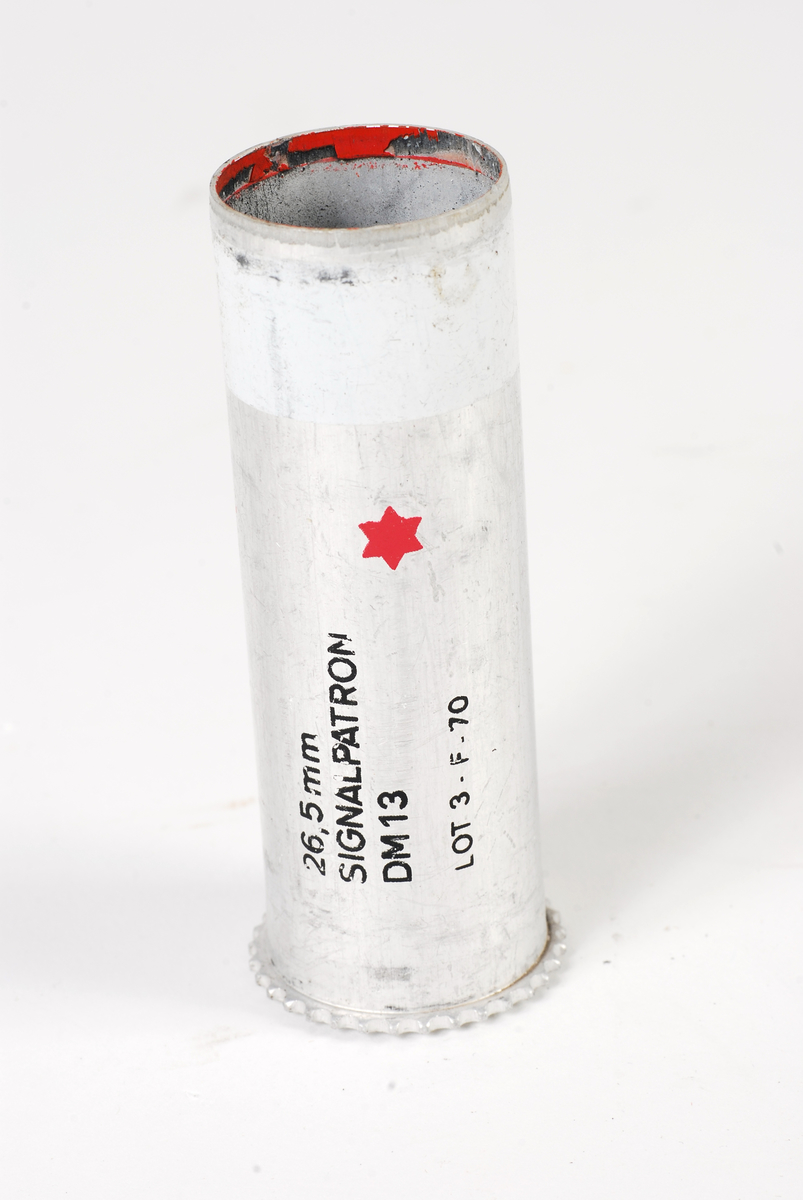 26,5 mm tomhylse til tyskprodusert signalpatron for det norske forsvaret. Hylseranden er serratert rundt det hele. 
Hylsen er merket.
26,5 mm
SIGNALPATRON
DM13
LOT 3-F-70