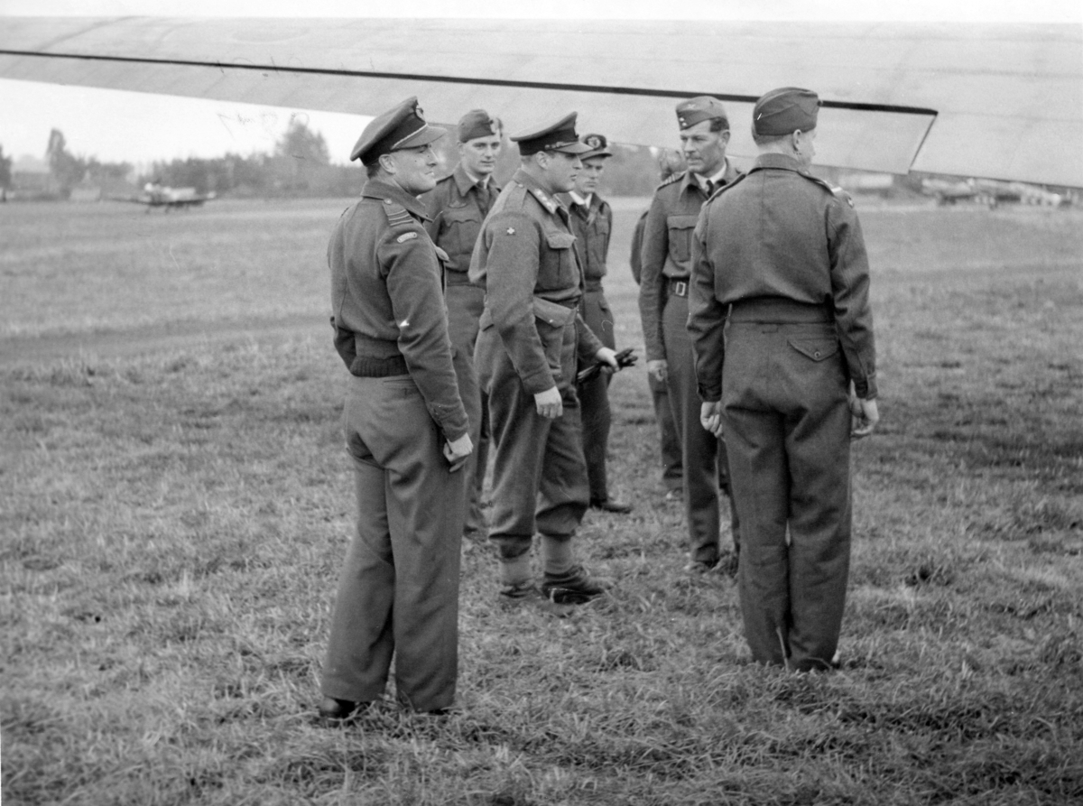 HKH Kronprins Olav på Grimsbergen flyplass, sammen med bl.a. oberstløytnant R.A. Berg (t.v.), kaptein "Zulu" Morris (t.h.) og Wilhelm Mohr (bakerst t.v.).