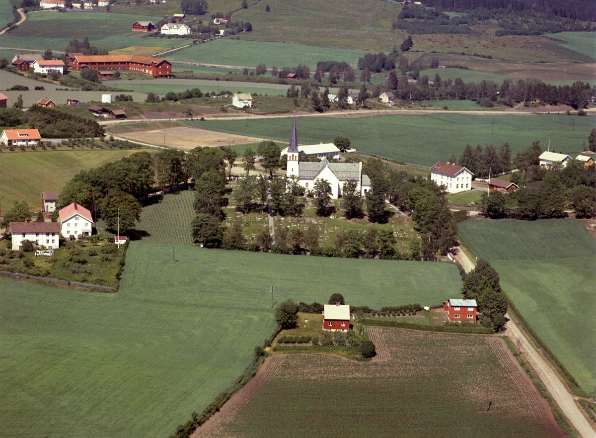 Flyfoto. Furnes Kirke, med Kirkenær skole bak. Boligen Rogne i nedre høyre. Stor-Deglum til høyre, Velt-Deglum venstre. Storlåven på Dæli i bakgrunnen