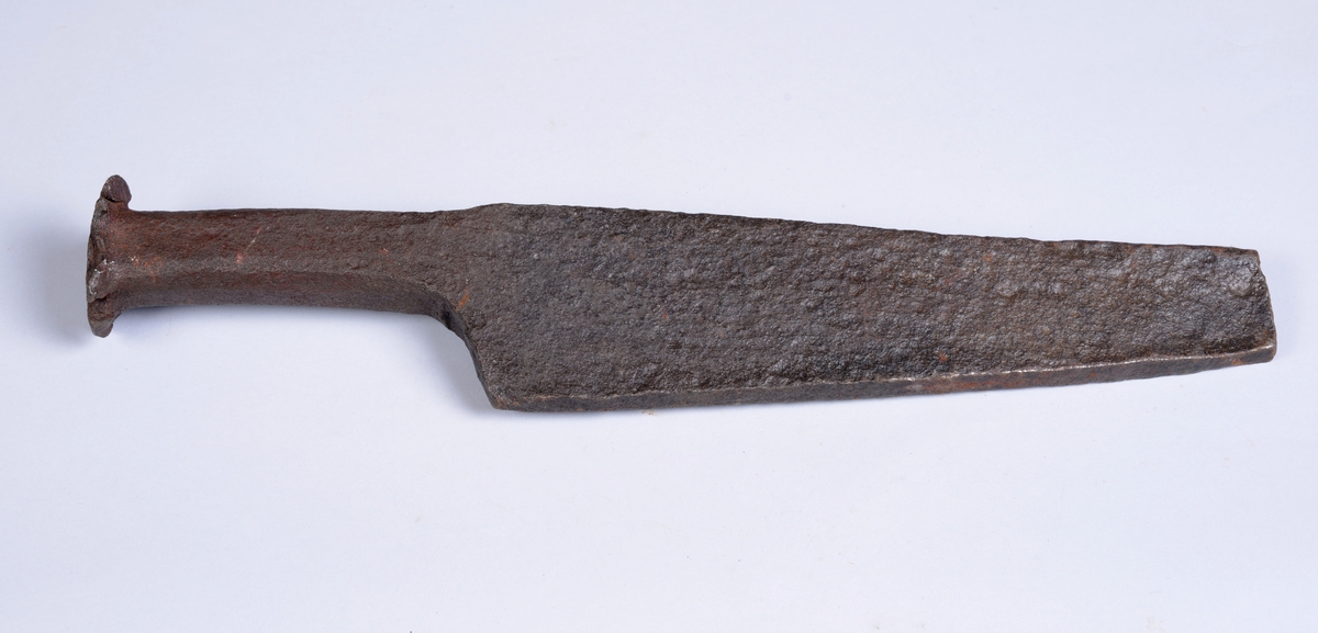 Knivformet kile i jern. Bladet er trekantformet. Enden er butt og "sprikende" som resultat av slag.