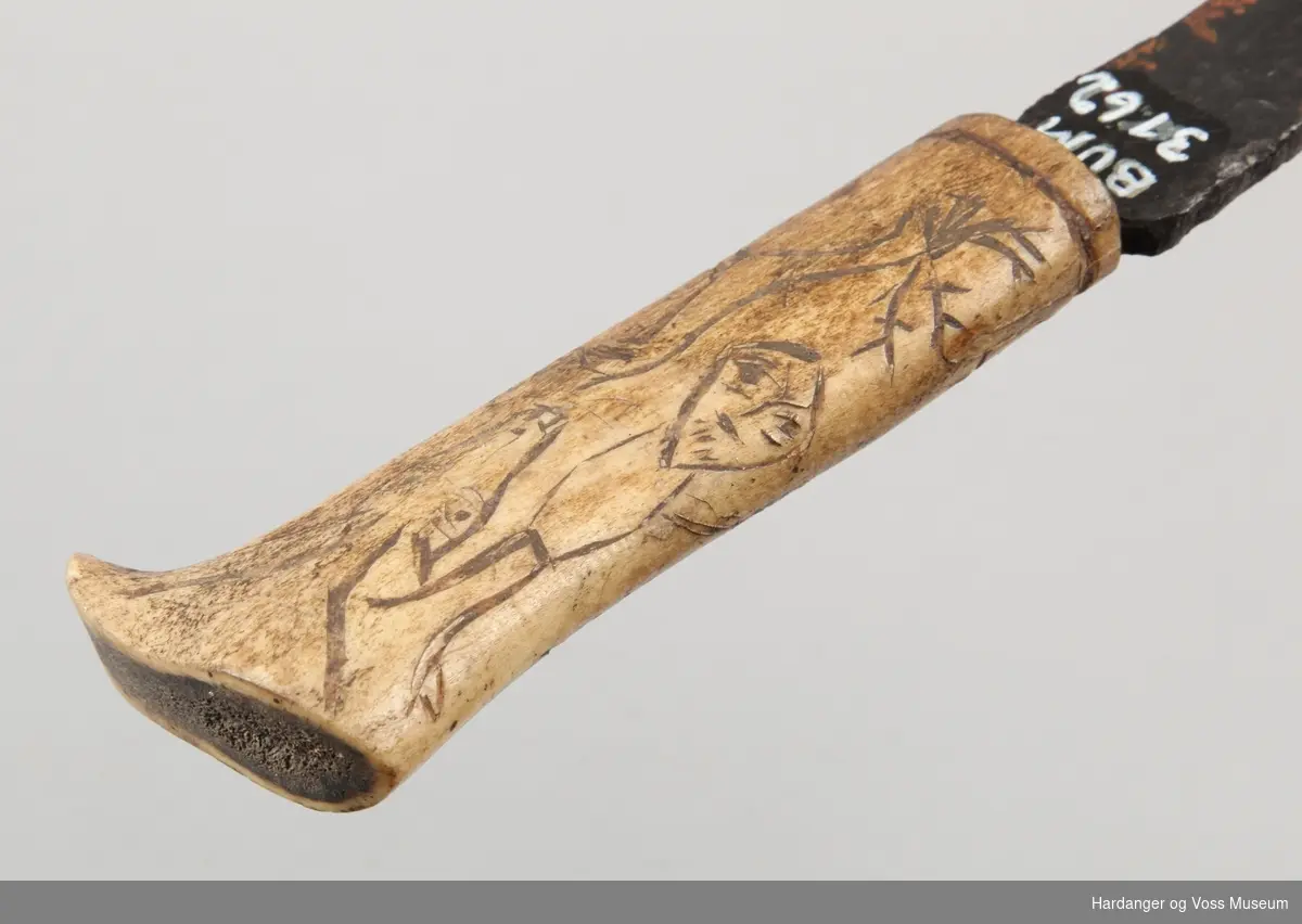 Dekor: Enkle teikningar av reinsdyr, menneske og tre på skaftet.

Knivbladet er av jarn og handtaket av bein.