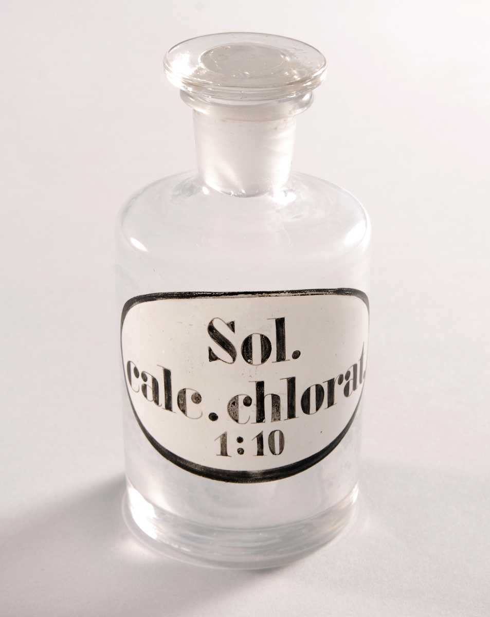 Flaske med flat islepet glasspropp
Oval innbrent etikett med sort kant
