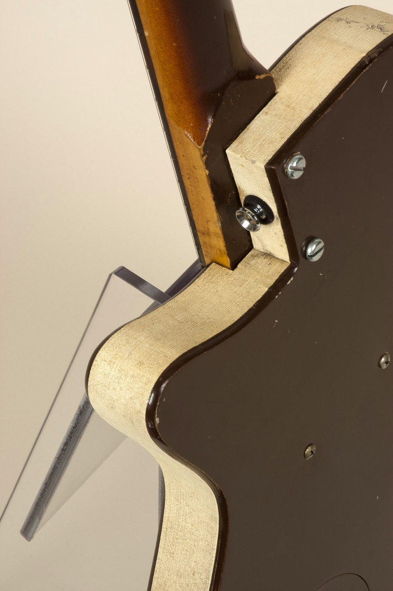 Elektrisk gitar (semi-hollow) med kropp av masonitt og furu, brunlakkert med en "sparkling finish" av metallic gull. Enkel cutaway. Hals av poppel. gripebrett av rosentre.  En enkel pickup, såkalt "lipstick". På grunn av formen på gitarhodet refereres den ofte til som "Coke-bottle headstock".