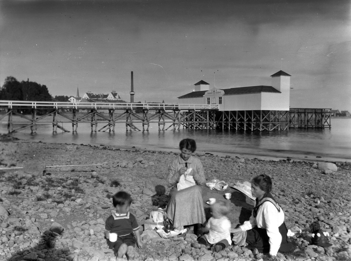 Hamar sjøbad, 2 kvinner og to barn på stranda ved badehuset som ble bygget i 1916, og revet i 1931. 