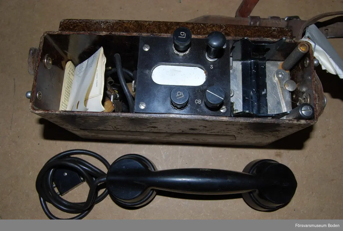 Telefonapparat m/1937 modifierad med klyka på 1950-talet, varvid modellåret ersattes av beteckningen MT (Med Tillbehör). Även bruksanvisning medföljer.