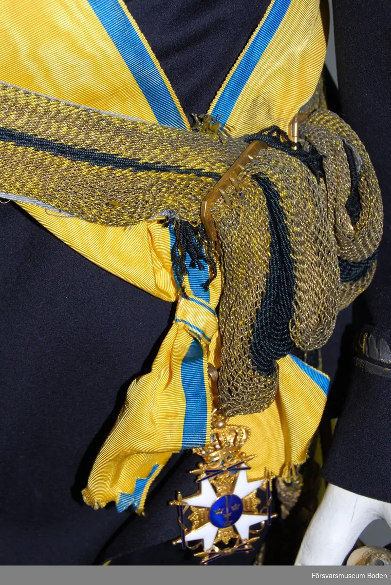 Vit emalj på korset, och korsade svärd med blå emalj på alla fyra sidor. Med tillhörande band som bars över axeln med ordenstecknet placerat vid höften.