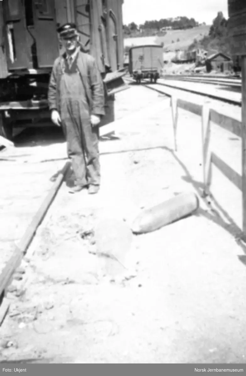 Dombås stasjon etter bombingen i 1940; fyrbøter Simensen ser på en udetonert bombe