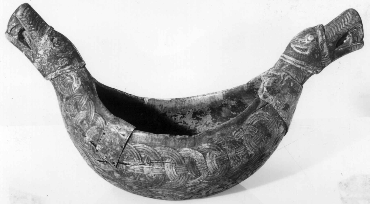 Bolle med håndtak formet som dragehovden. Flatskurd dekor: Geoometrisk bånd. Polykrom maling i flere lag.