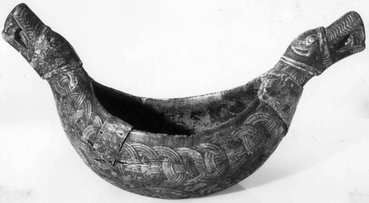 Bolle med håndtak formet som dragehovden. Flatskurd dekor: Geoometrisk bånd. Polykrom maling i flere lag.