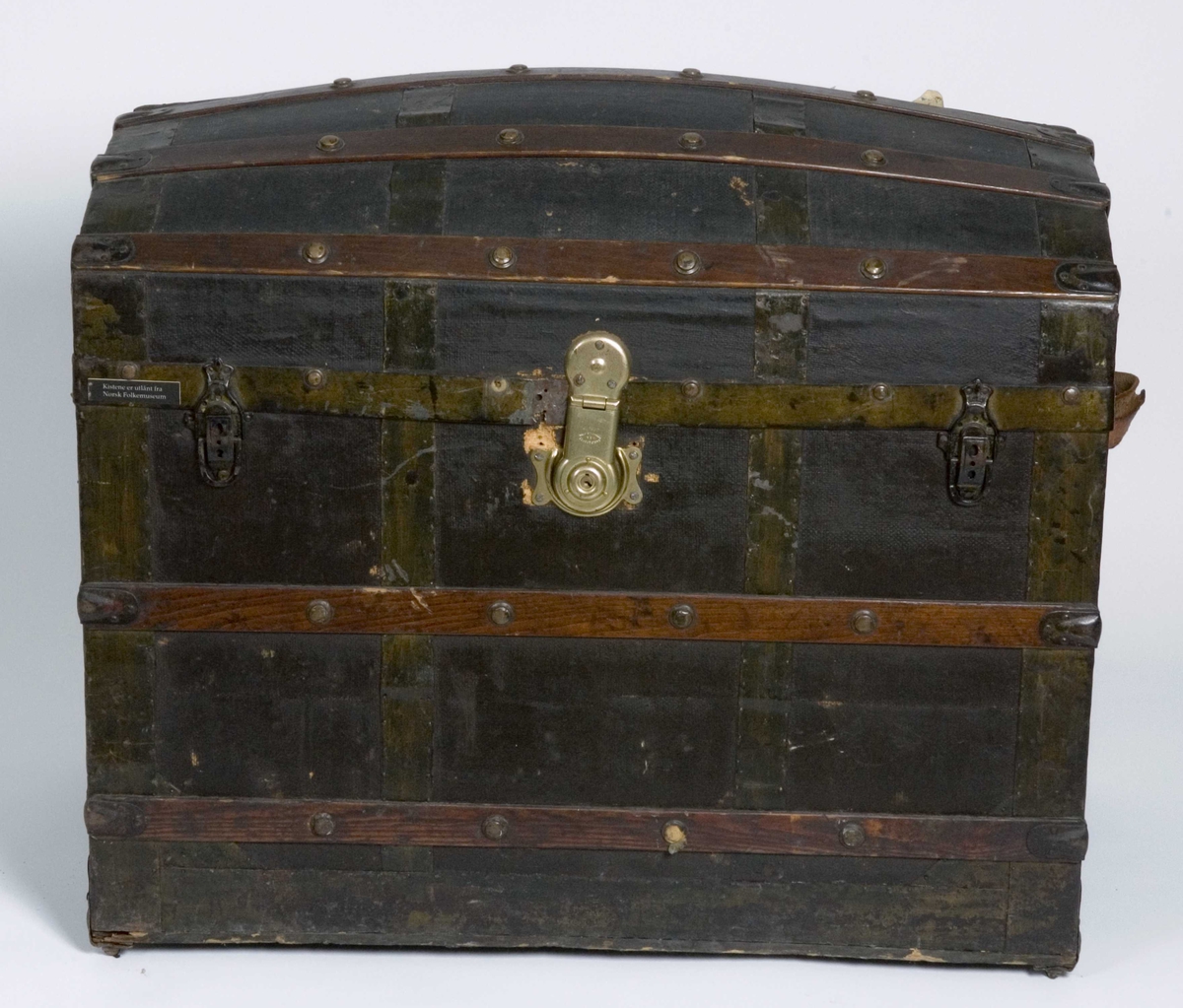 Koffert i kisteform med buet lokk, beslått med jernblikk og trelister. Innvendig utkledd med papir og tekstil.