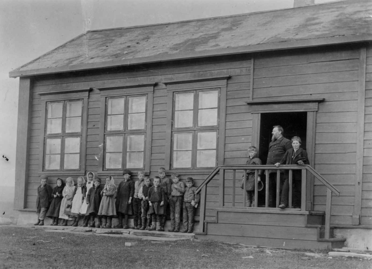 Vestre Jakobselvs første skole, Vadsø, Finnmark. Lærer Thomas Lilleeng med sine elever foran skolen. Fotografert i 1890-årene.