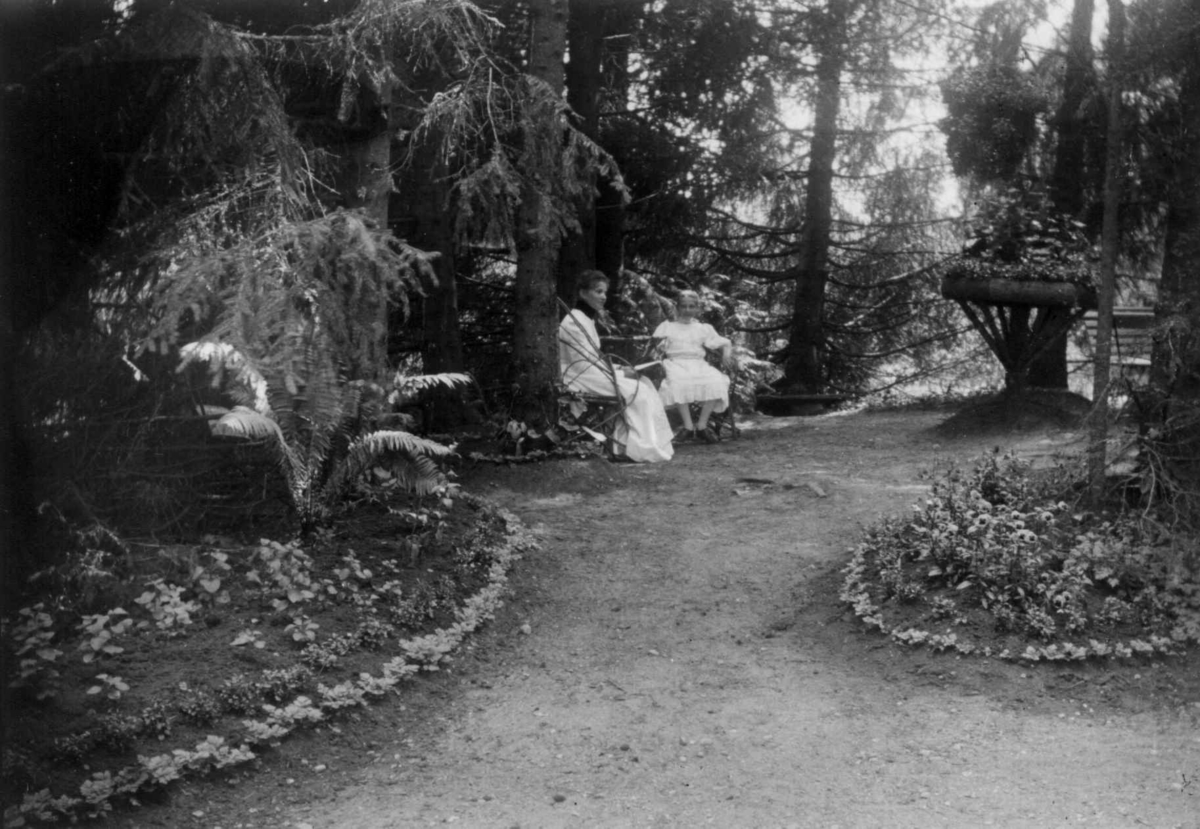 Dal gård, fra parken. Kvinne og pike på benk.
Fra serie fotografert av kammerherre Fredrik Emil Faye (1844-1903), gårdens eier.