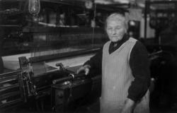 Brynnela Orland står ved veven på fabrikken