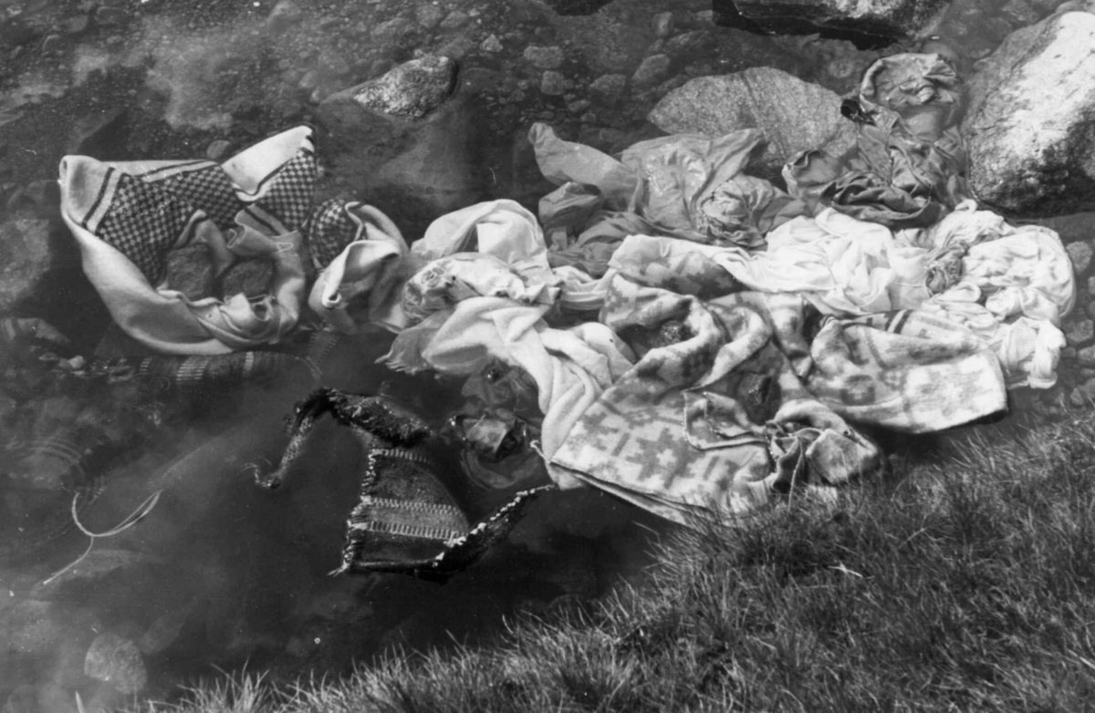 Vasking av klær i kvernhusbekken på Smeland. Steiner er lagt oppå klærne så de ikke skal renne med strømmen. Åseral, Vest-Agder 1943.
