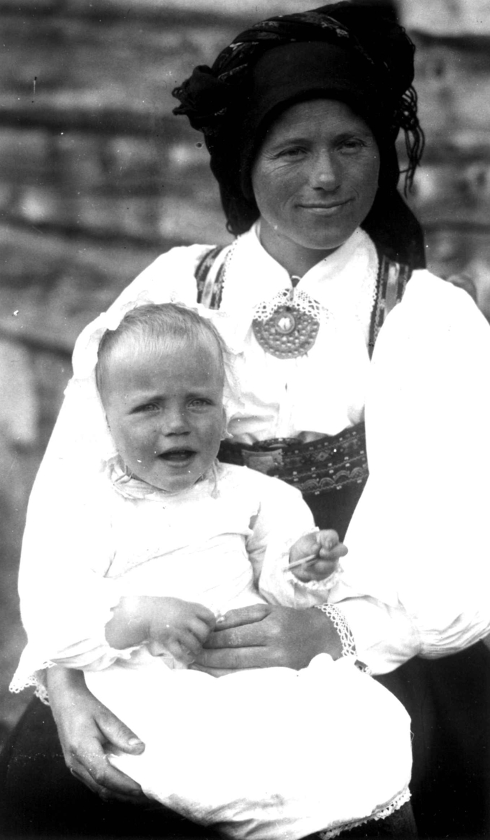 Kvinne- og barnedrakt, gruppeportrett, Valle, Setesdal, Aust-Agder, antatt 1924. Kvinne med spedbarn på fanget. Fra "De Schreinerske samlinger" (skal oppgis).