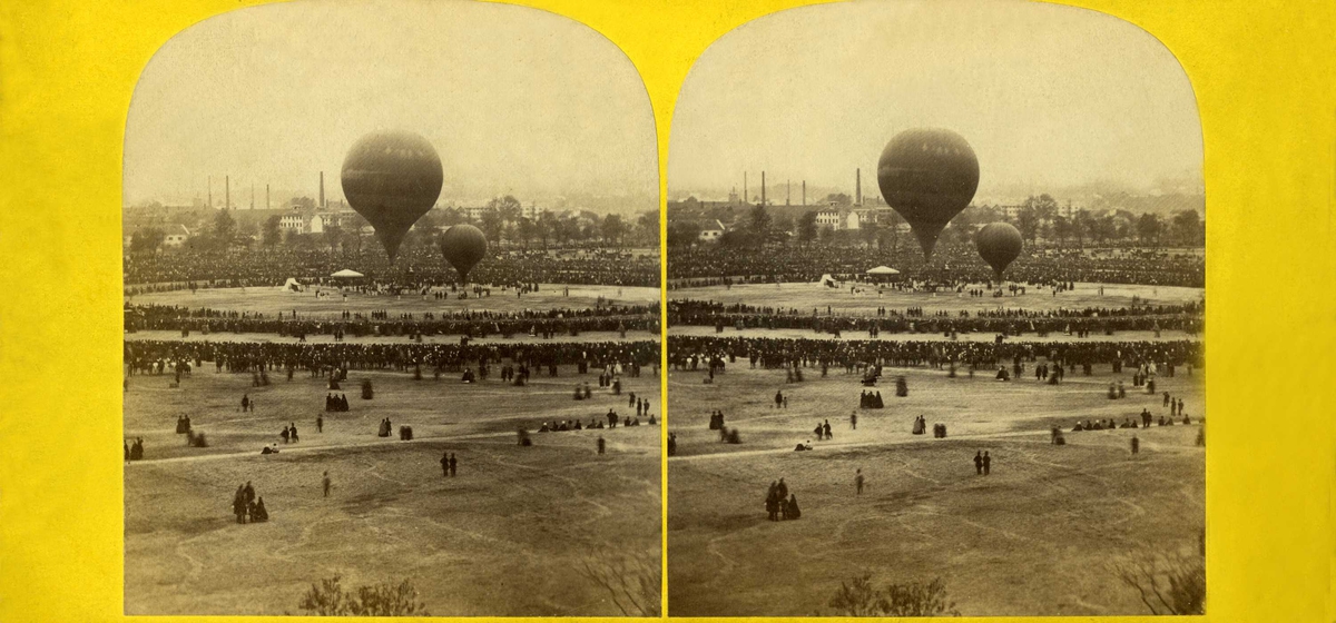 Antatt Champ de Mars i Paris i oktober 1863.
Stereoskopi. Åpen plass med mennesker og to luftballonger.