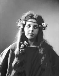 Studioportrett av kvinne i kostyme med mørk overdel og bloms