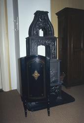 Et skjermbrett med dekor og pynt i messing foran en etasjeov