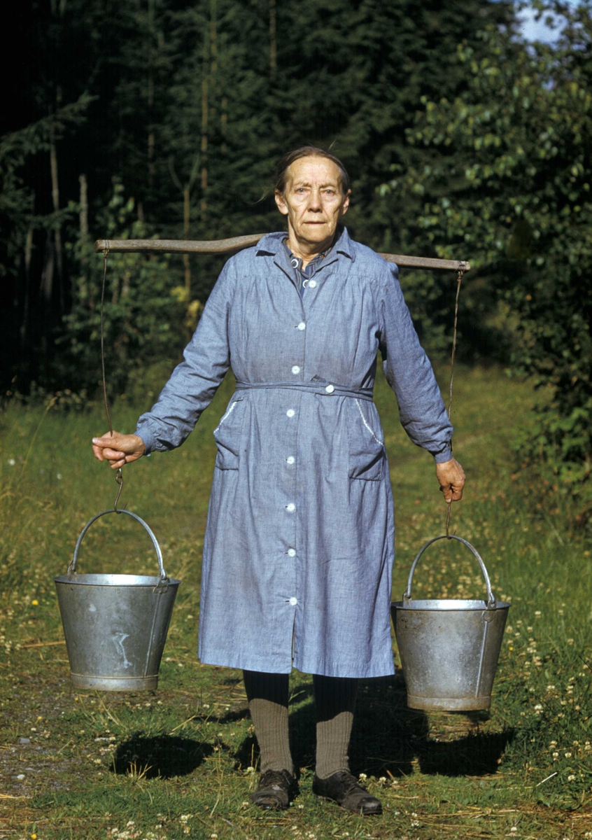 Portrett av kvinne som bærer vann. Mor til Alf Prøysen, Julie Mathiasdatter. Avbildet i Prøysen, Ringsaker, Hedmark.
