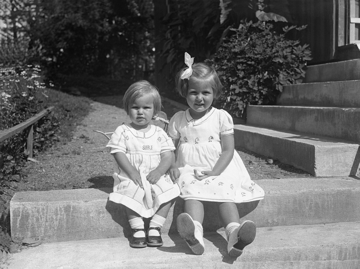 Søstrene Siri og Guri sitter sammen på en trapp i hagen i P.T. Mallings vei 4, Bygdøy. Fotografert juli 1932.