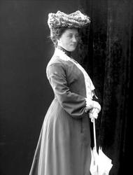 Portrett, kvinne i spaserdrakt med hatt og parasoll. Inga Ød