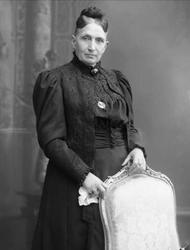 Portrett, eldre kvinne i mørk drakt. Fru Sinclaire.