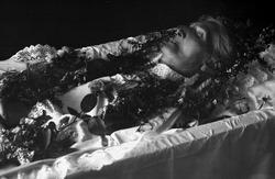 Post mortem-fotografi. Død kvinne i pyntet kiste.