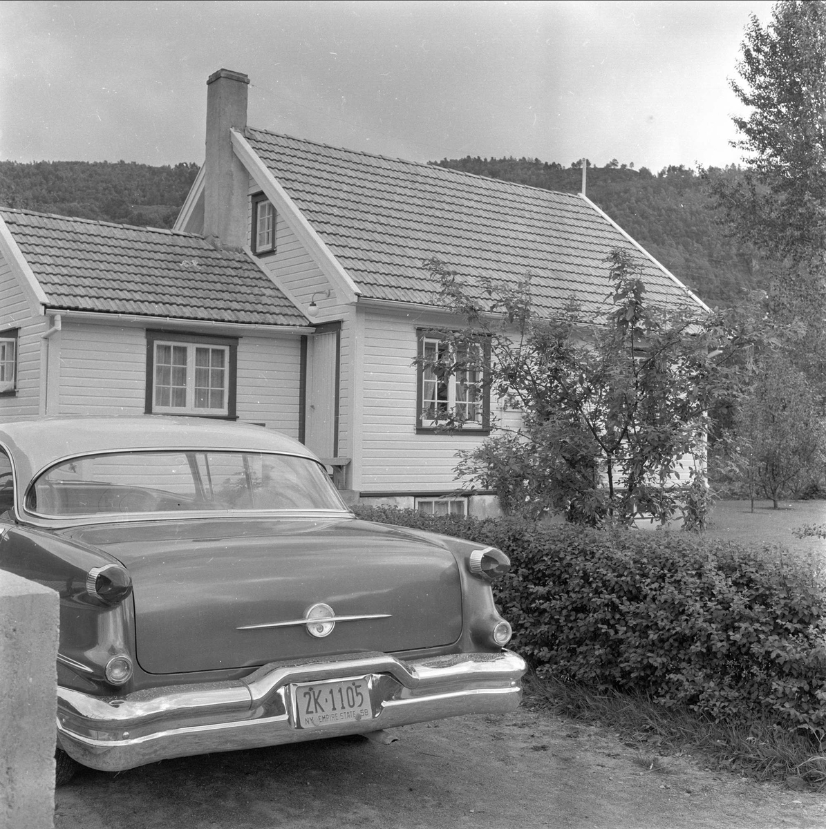 Kvinesdal, Vest-Agder, august 1958. Norskamerikanere i Kvinesdal. Bil foran hus.