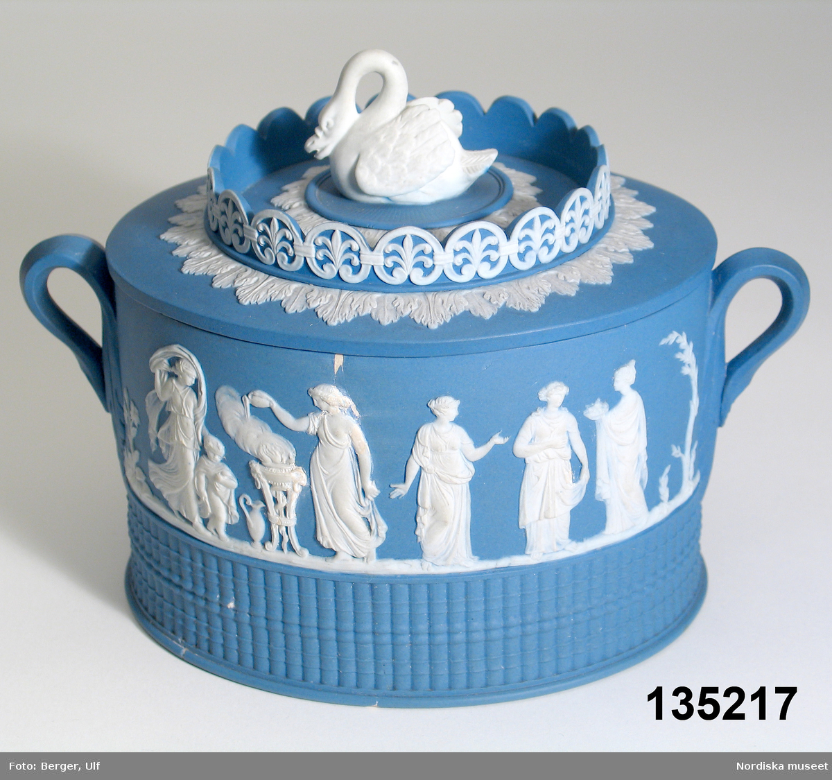 Text i Dukade bord: "Sockerskål av blå "jasper ware" med pålagd dekor i Wedgwoodstil. Stämplad "ADAMS" = William Adams & Sons
Ltd, Tunstall and Stoke, Staffordshire, England.
Stämpeln användes 1787-1805. "
