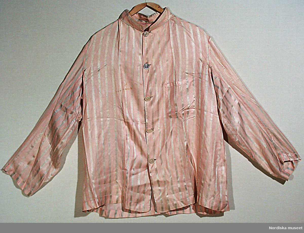 Pyjamas, rock (a) och byxor (b), av siden, rosa och grå ränder. Snodd m. 2 tofsar. Knappar av pärlemor.